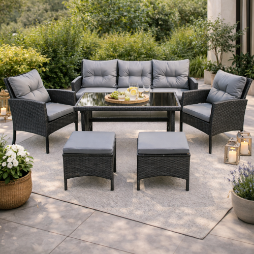 Meble ogrodowe z technorattanu w szarym kolorze sofa 2 fotele 2 pufy w aranżacji ogrodowej